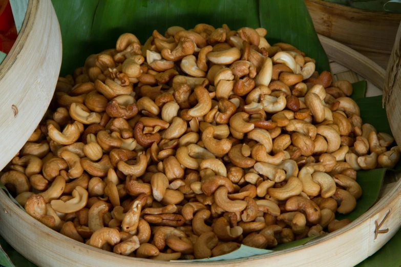 a wooden bowl filled with peanuts on top of a green surface