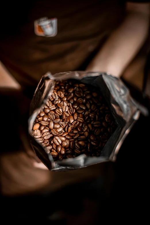 a person holding a bag of coffee beans, by Frederik Vermehren, pexels contest winner, award - winning crisp details ”, 1 6 x 1 6, foil, australian