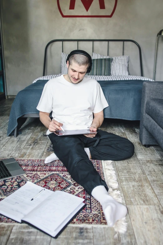 a man sitting on the floor reading a book, an album cover, by artist, khabib, headphones on his head, in my bedroom, wearing pants and a t-shirt