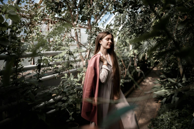 a woman standing in a greenhouse surrounded by plants, a picture, pexels contest winner, renaissance, wearing a long coat, asian girl with long hair, cinematic outfit photo, girl with brown hair