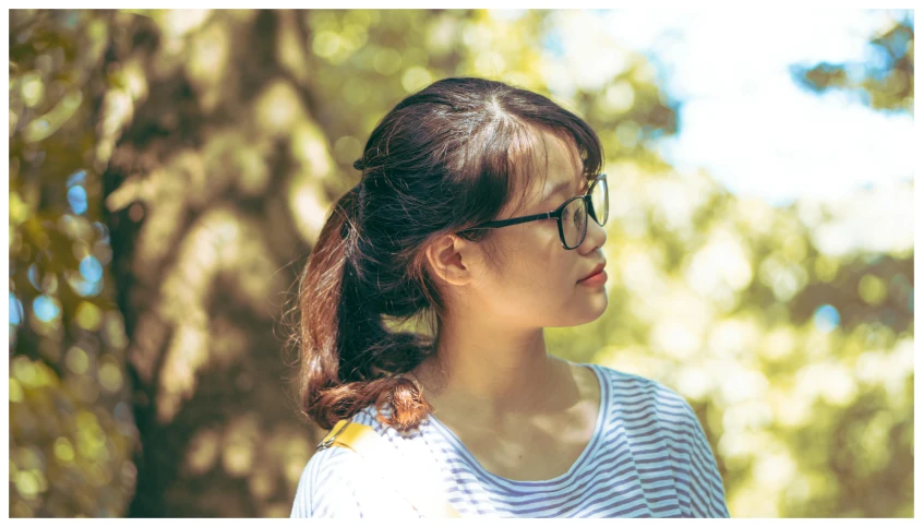 a woman wearing glasses and a striped shirt, by Tan Ting-pho, unsplash, realism, pony tail, sunny day time, profile image, square rimmed glasses