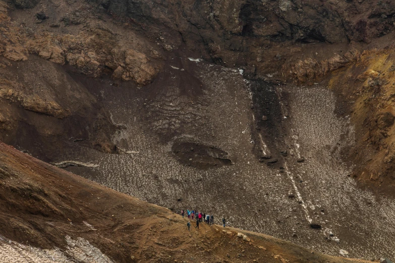 three people climbing the side of a hill next to brown and tan cliffs