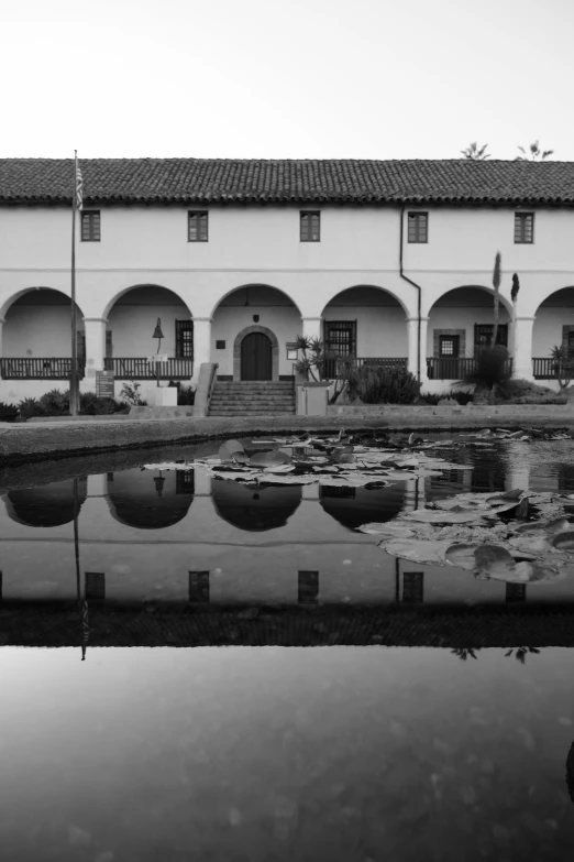 a black and white photo of a building with a pond in front of it, by Ansel Adams, flickr, the city of santa barbara, symmetry!! water, mission arts environment, ffffound