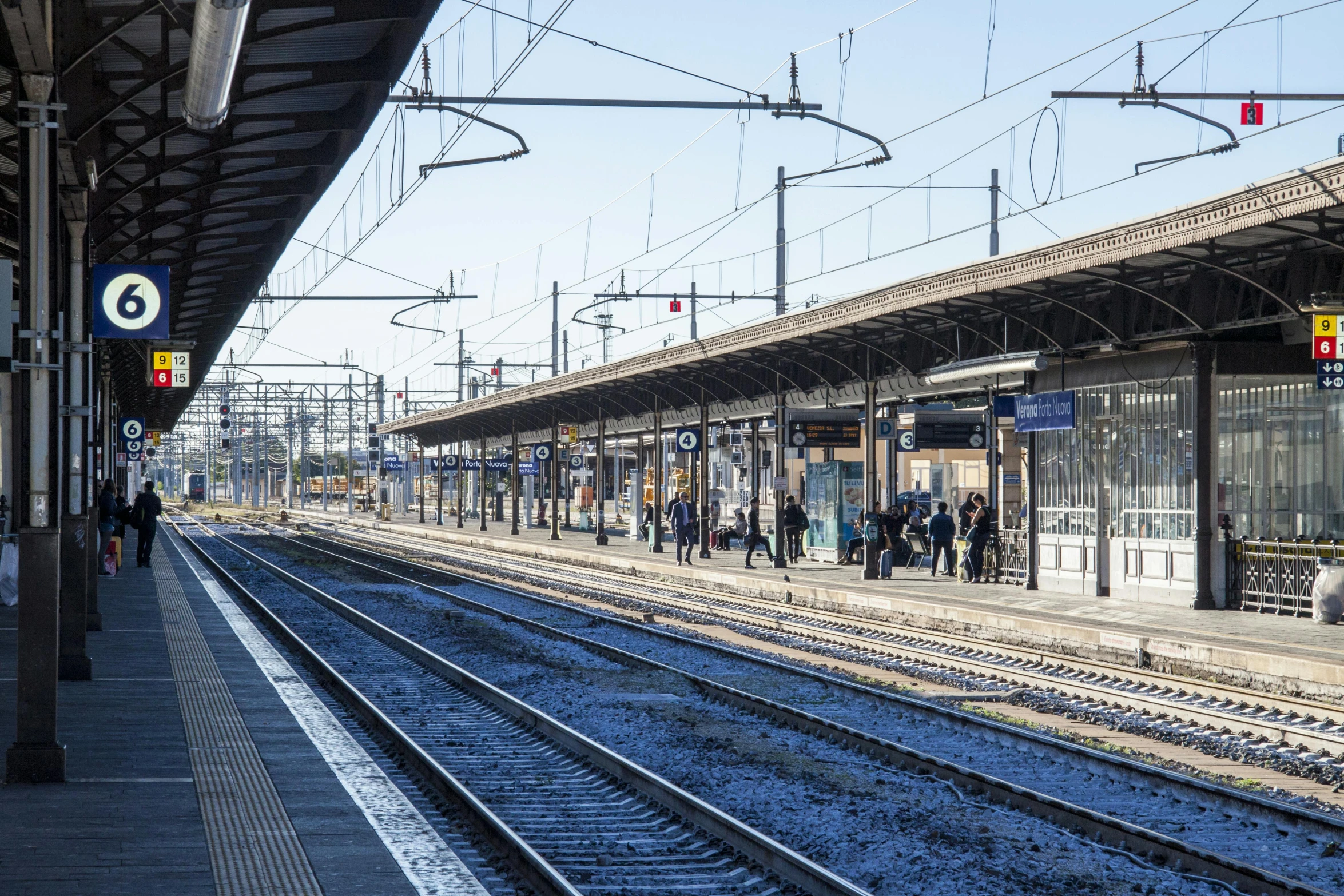 a train station with people waiting for the train, by Francesco Furini, view from the distance, 2022 photograph, sunny day time, thumbnail