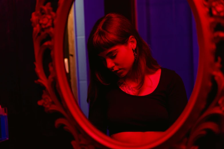 a woman standing in front of a mirror, an album cover, inspired by Elsa Bleda, pexels contest winner, red and blue black light, teenage girl, red room, night life