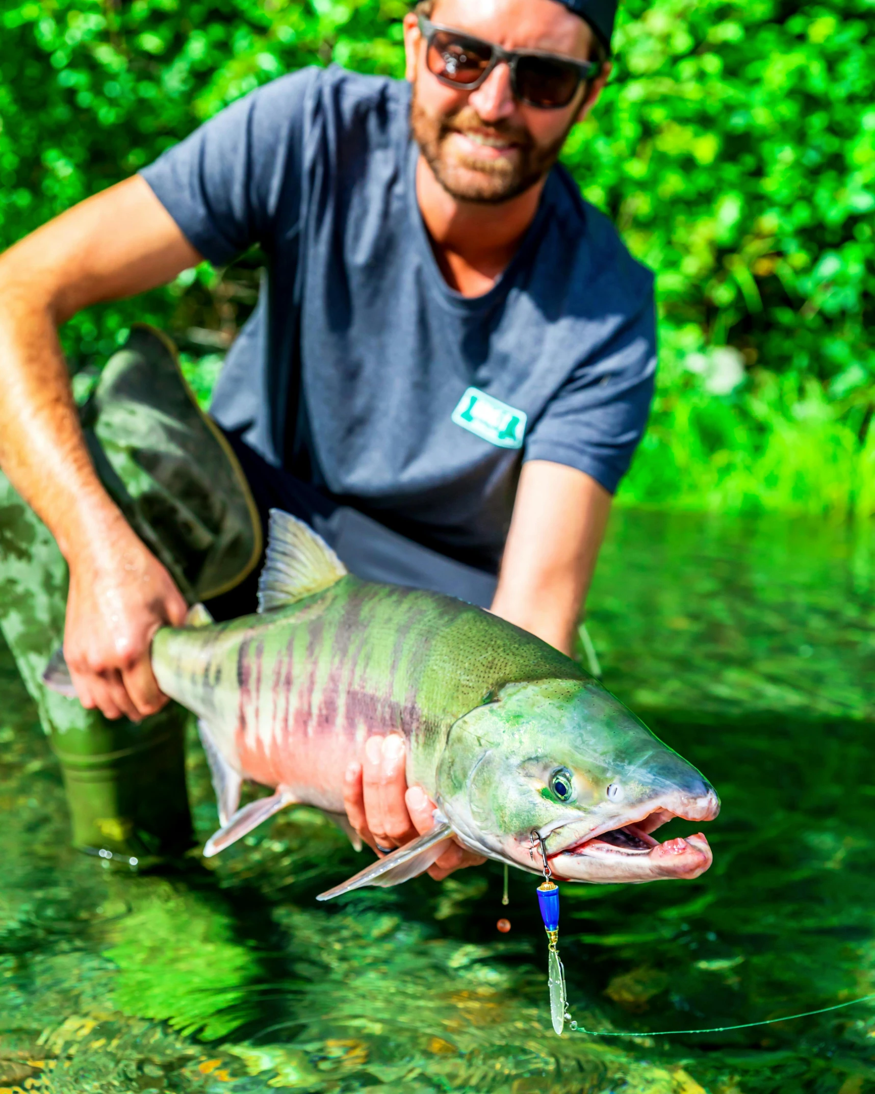 a man holding a fish in a river, blue and green water, profile image, thumbnail, chomatic aberration