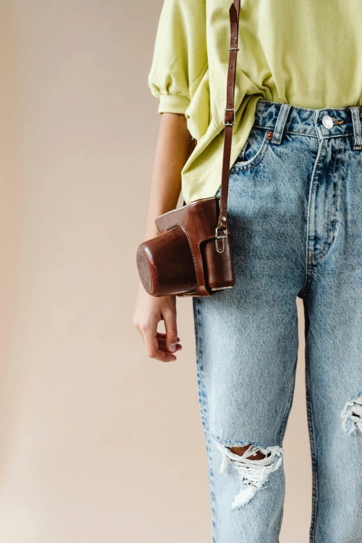 a woman in blue jeans holding a brown purse