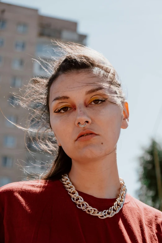 a woman standing in front of a tall building, an album cover, inspired by Elsa Bleda, trending on pexels, renaissance, bright piercing brown eyes, nonbinary model, headshot portrait, phoebe tonkin