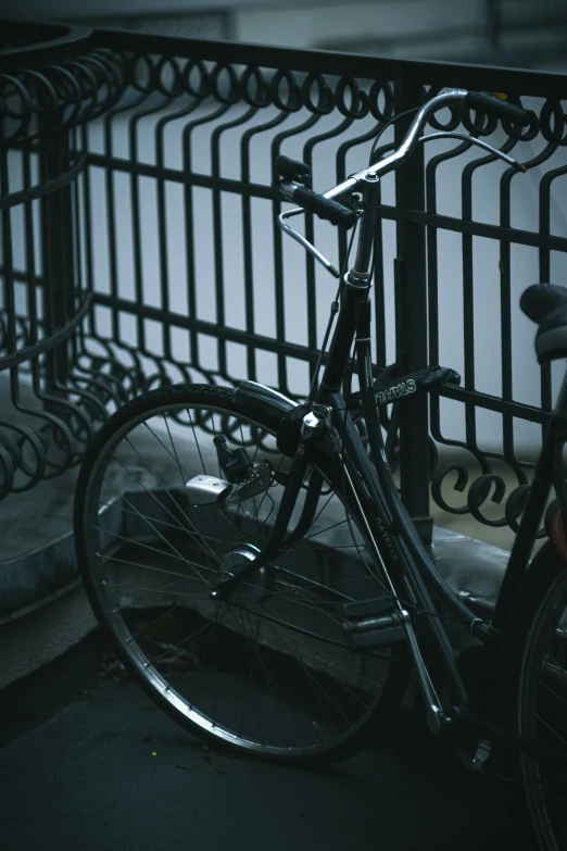 a bicycle is parked next to a fence, black on black, up close, low quality photograph, multiple stories