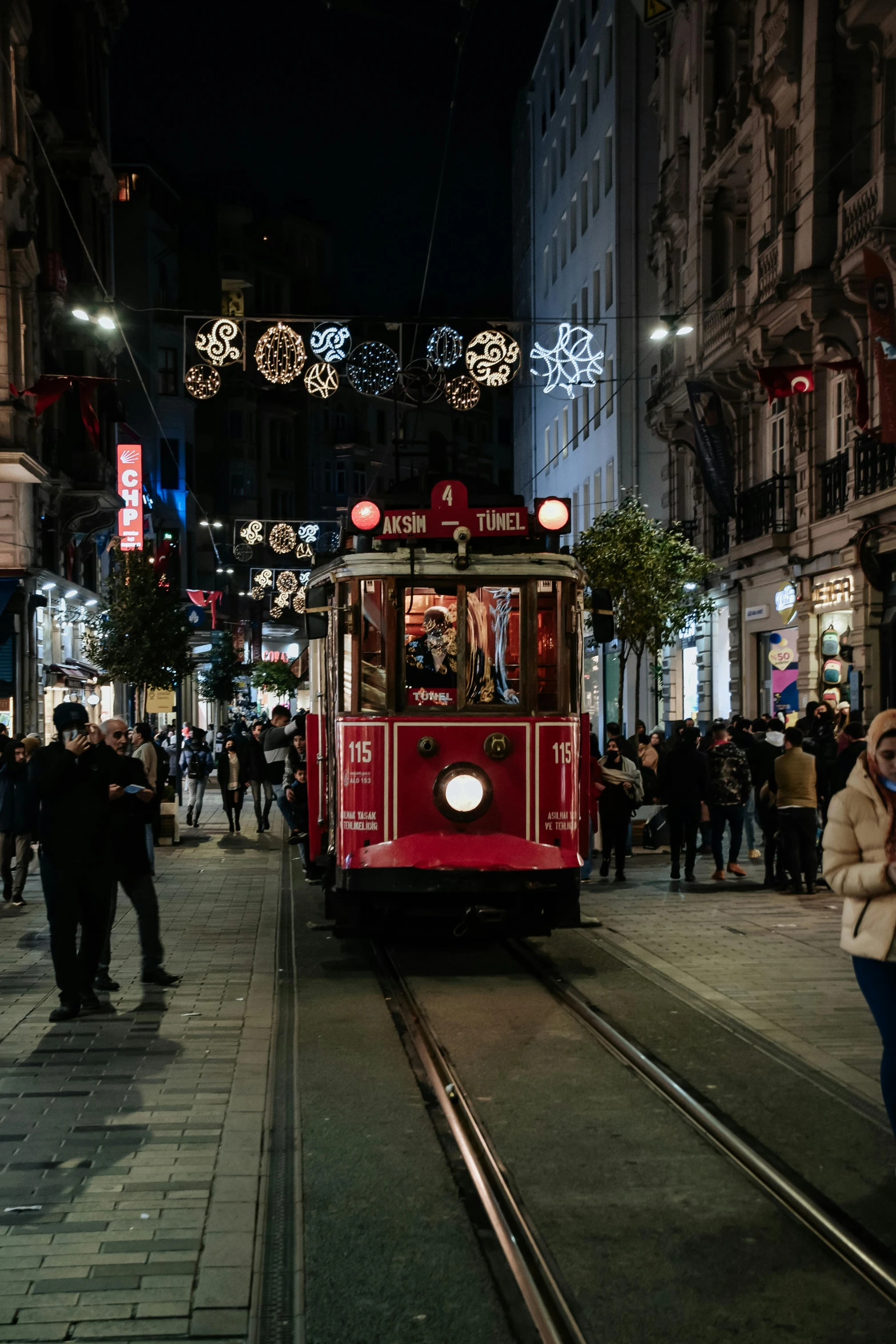 a trolly pulling up to people on a street at night