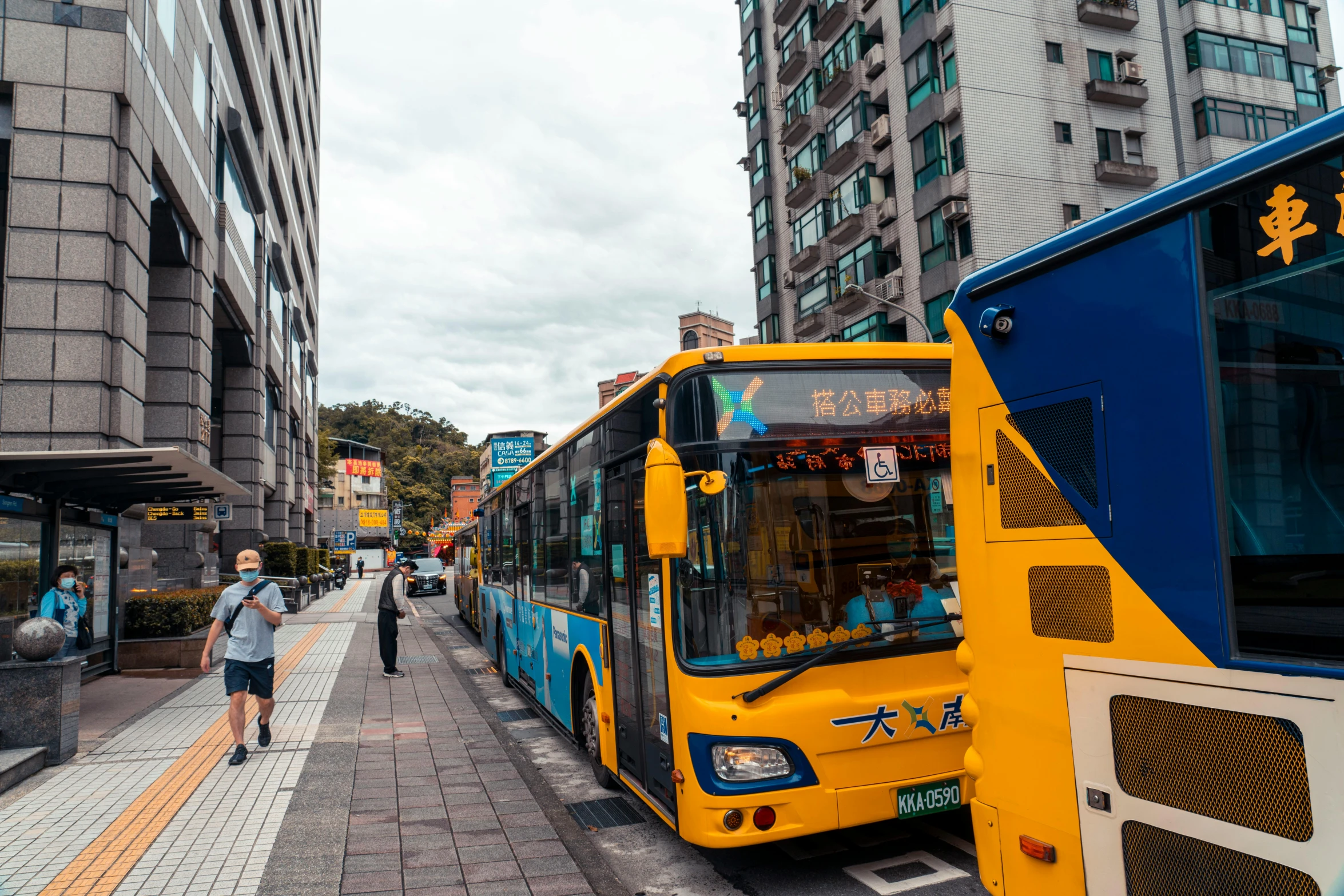 a person that is walking on a sidewalk with a bus