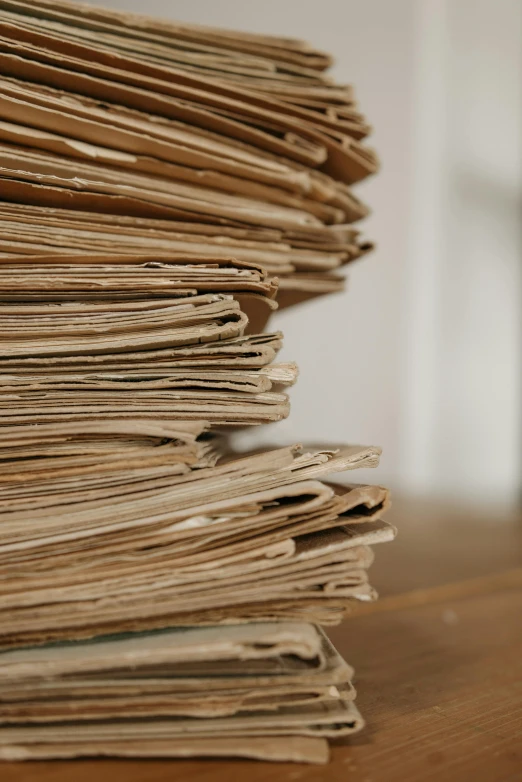 a stack of newspapers sitting on top of a wooden table, by Jakob Häne, private press, parchment paper, medium close - up, hay, cardboard