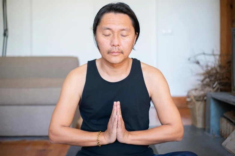 a man sitting in a yoga pose on a wooden floor