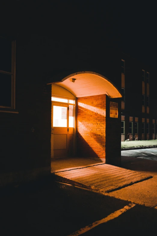 a person walking out of a building at night, an album cover, by Andrew Domachowski, unsplash, harsh sunlight, secret entrance, in an american suburb, door to lab