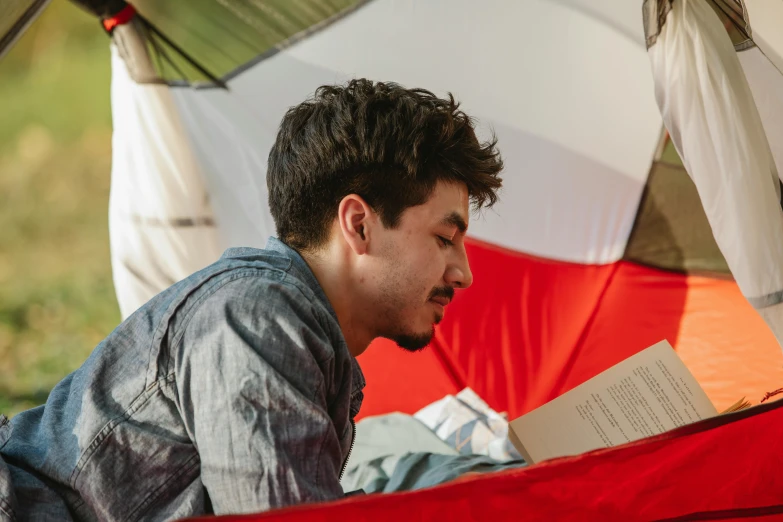 a man reading a book in a tent, pexels contest winner, holding a red banner, shia labeouf, profile image, student