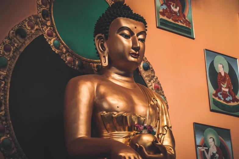 a golden buddha statue next to paintings on the wall