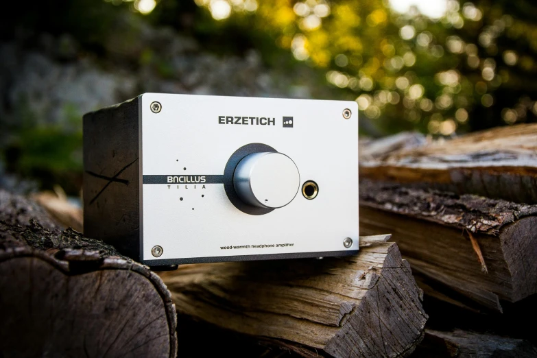 a white radio sitting on top of a pile of wood, an album cover, by Kristian Zahrtmann, unsplash, bauhaus, in front of a forest background, circuitry. 8k 3d geology, sennheiser, zenith angle