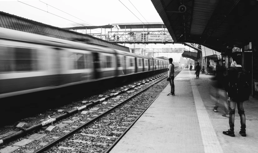 a black and white photo of a train pulling into a station, a black and white photo, pexels contest winner, indore, man standing, speed lines, waiting to strike