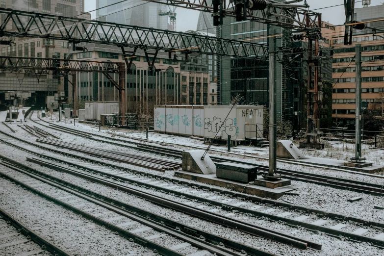 a train traveling down train tracks next to tall buildings, inspired by Thomas Struth, unsplash contest winner, ground covered with snow, platforms, thumbnail, heavy lines