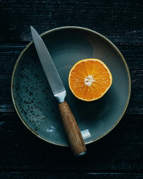 a knife sitting on top of a plate next to an orange, by James Morris, pexels contest winner, grey, thumbnail, bowl, multiple stories