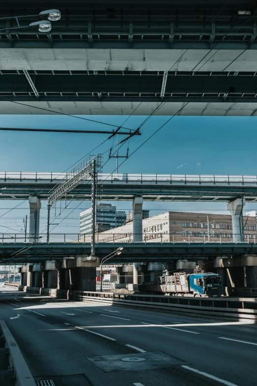 a train traveling under a bridge over a street, a picture, by Tobias Stimmer, unsplash, modernism, blue sky, in tokio, industrial complex, 🚿🗝📝