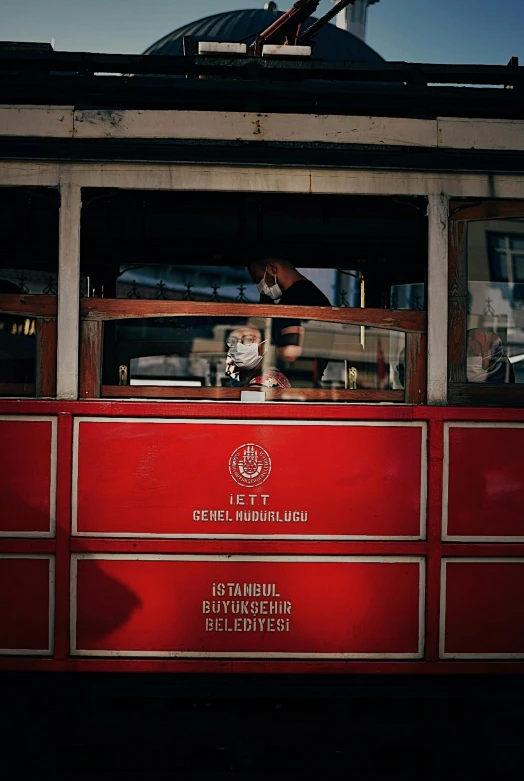 a man sits inside an old red trolley car