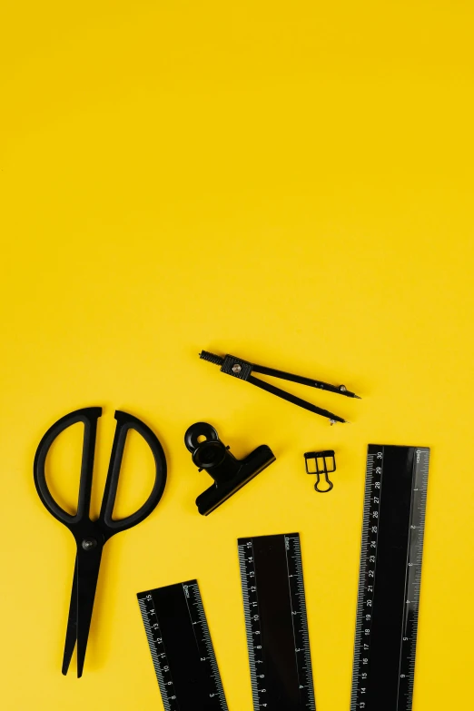 a pair of scissors and a ruler on a yellow background, trending on unsplash, academic art, black. yellow, various items, dark. no text, school curriculum expert