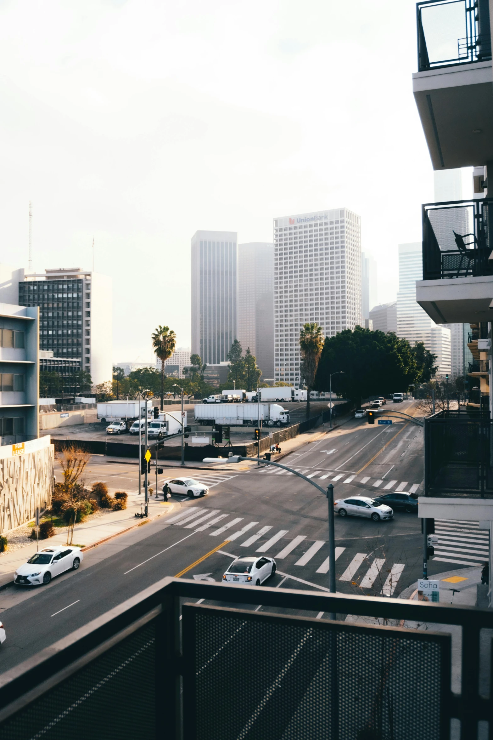 a city street filled with lots of traffic next to tall buildings, inspired by L. A. Ring, unsplash, modernism, low quality photo, cinematic morning light, skyline view from a rooftop, grain”