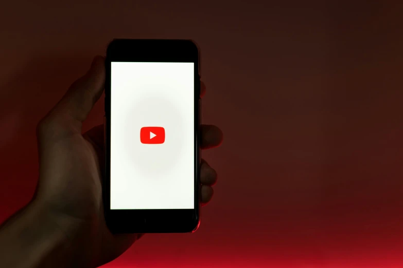 someone holds up their cell phone with youtube on the screen