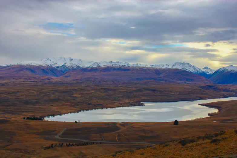 this scenic view shows a large lake and mountains, surrounded by dry grass