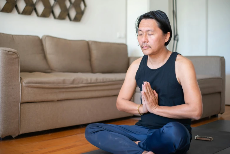 a man sits in a yoga position on a hard wood floor