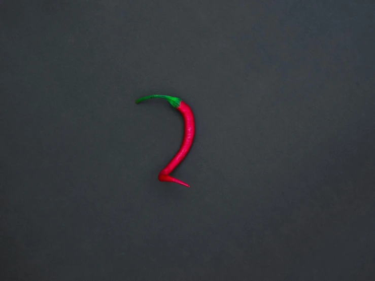 a red chili sitting on top of a black surface, trending on pexels, postminimalism, question marks, two colors, red green, type - 2