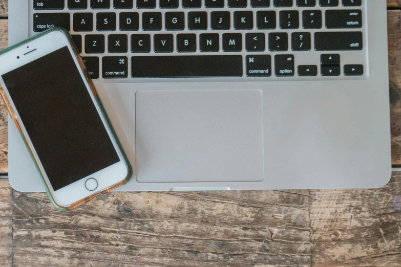 a cell phone sitting next to a laptop computer, by Carey Morris, pexels, on a wooden tray, grey, ergonomic, apple