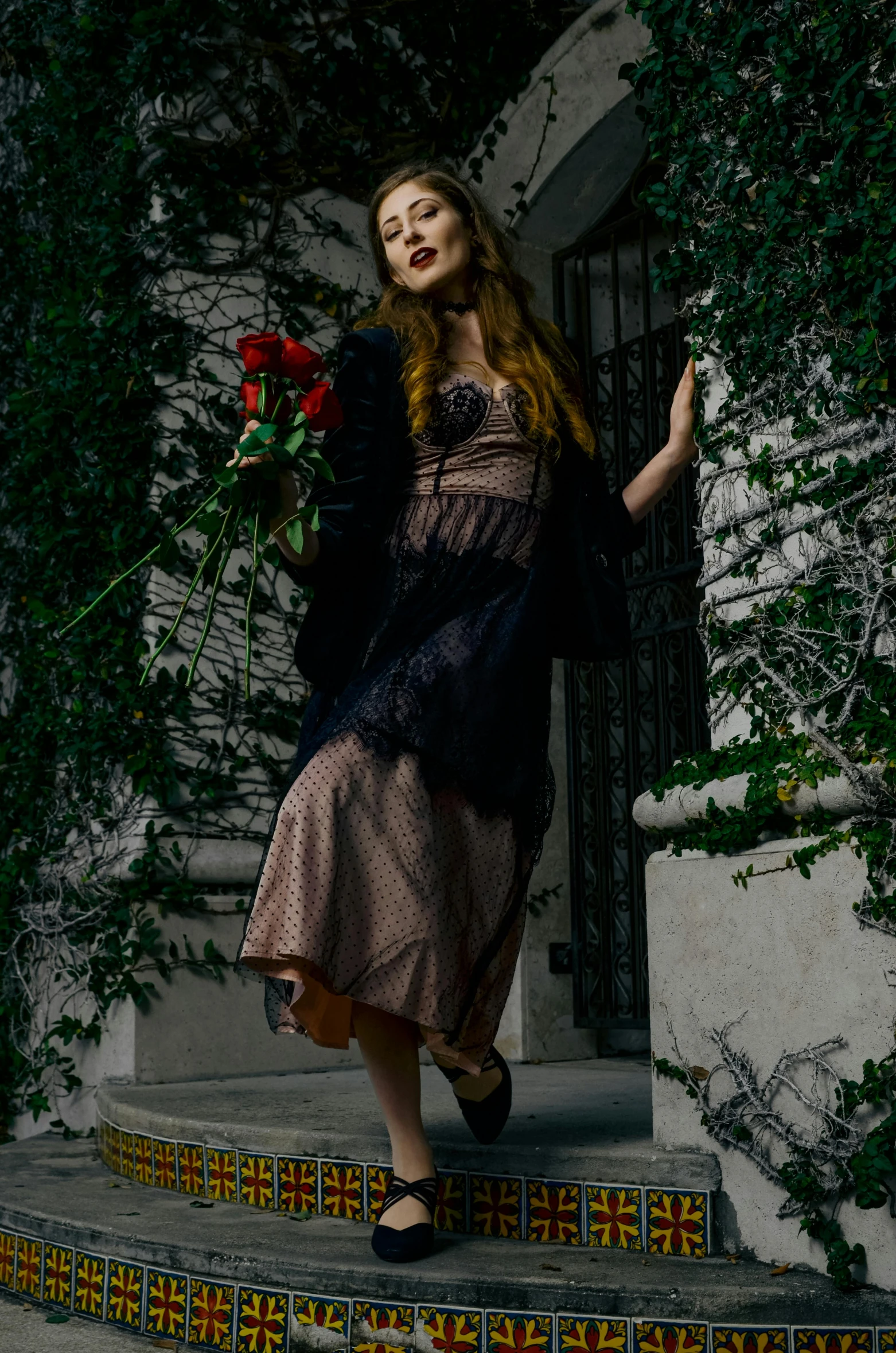 a woman in a long black dress holding roses