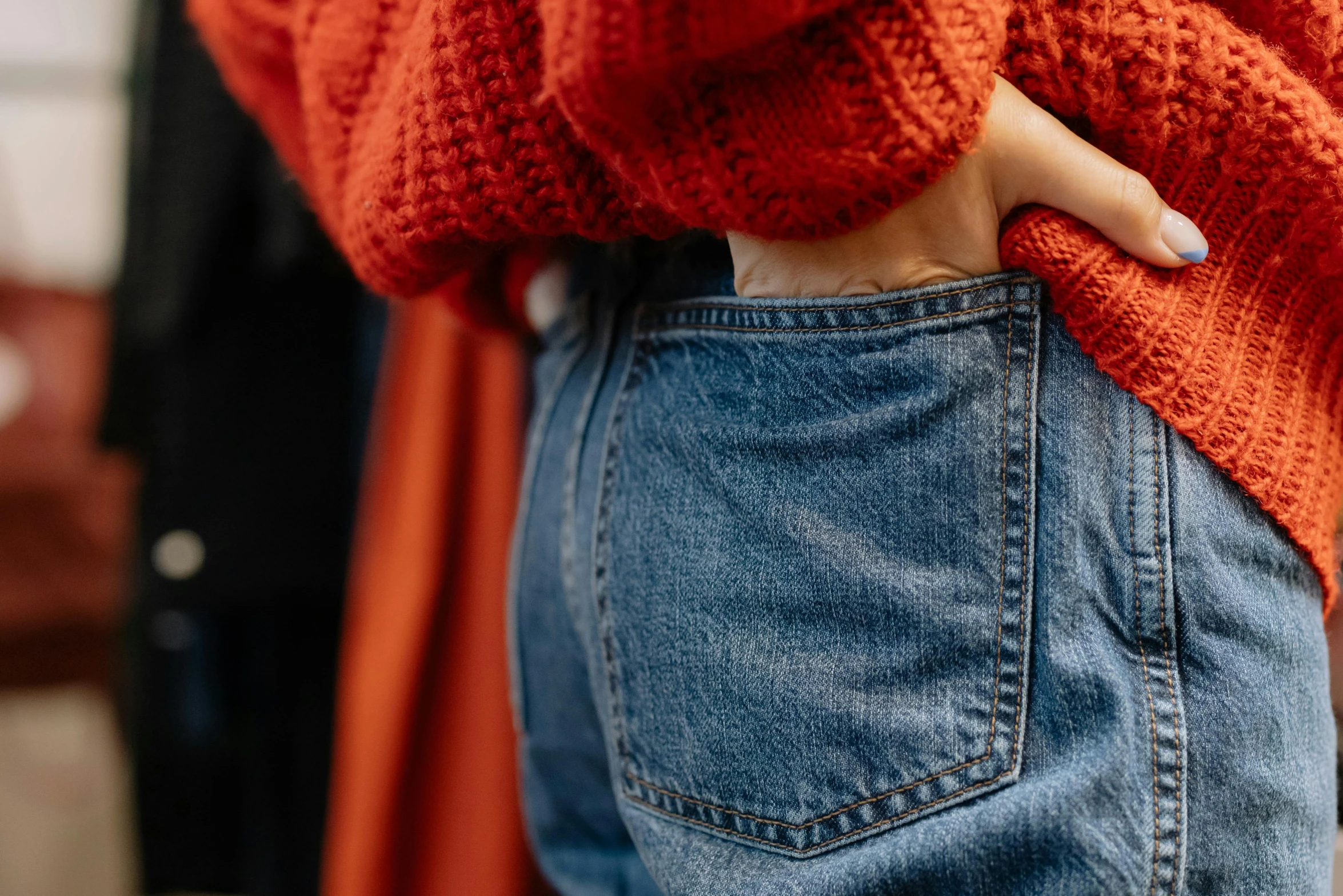 a woman in a red sweater standing with her  on a pair of jeans