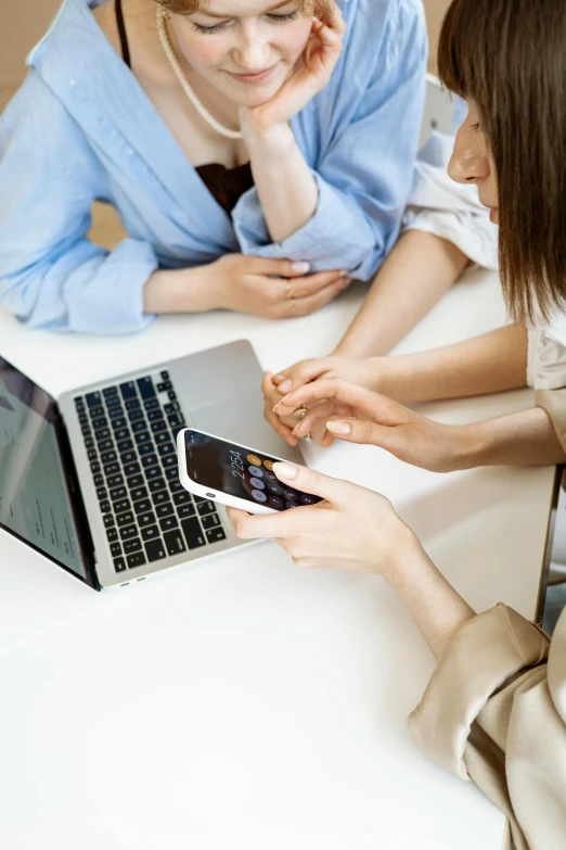 a couple of women sitting at a table with a laptop, corporate phone app icon, zoomed in, square, high-quality photo