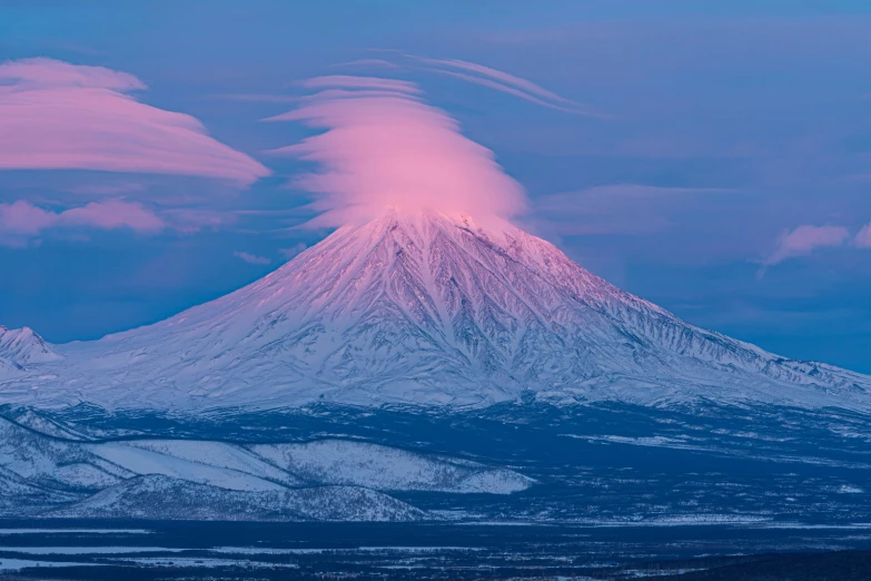 a large cloud looms in the sky above a mountain