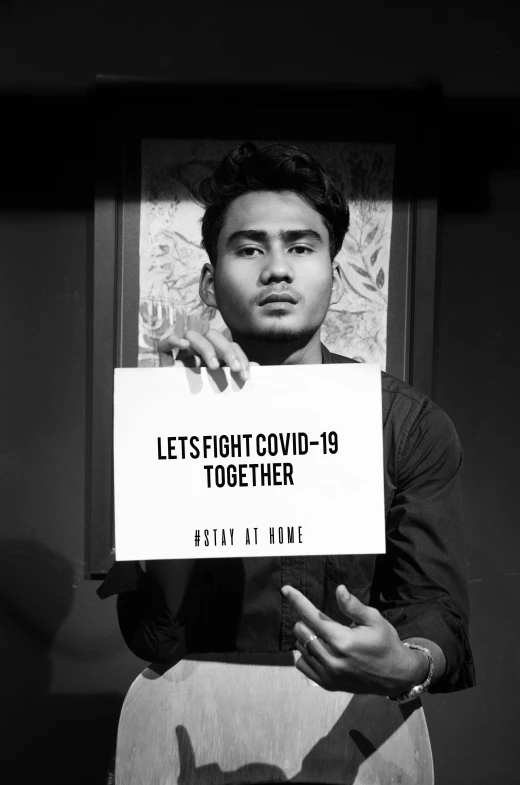 a young man is holding a poster with an ad in front of him