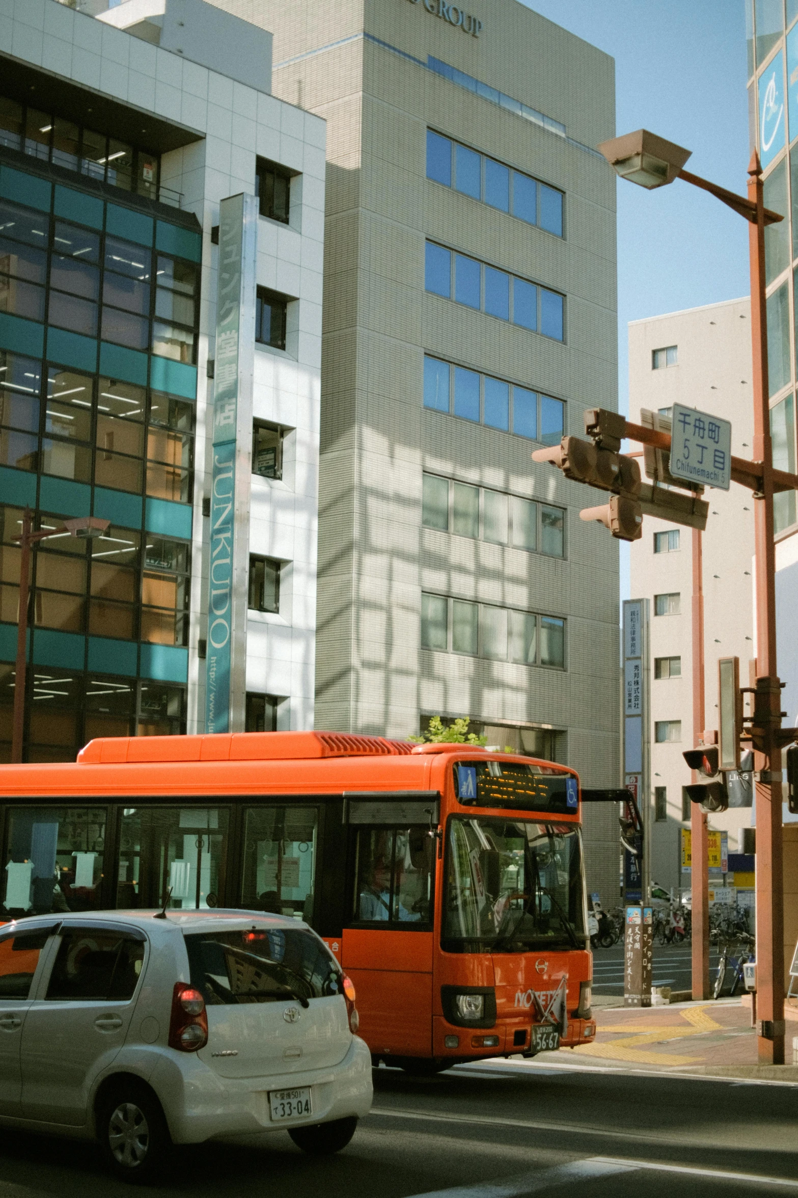 two buses driving down the street beside buildings