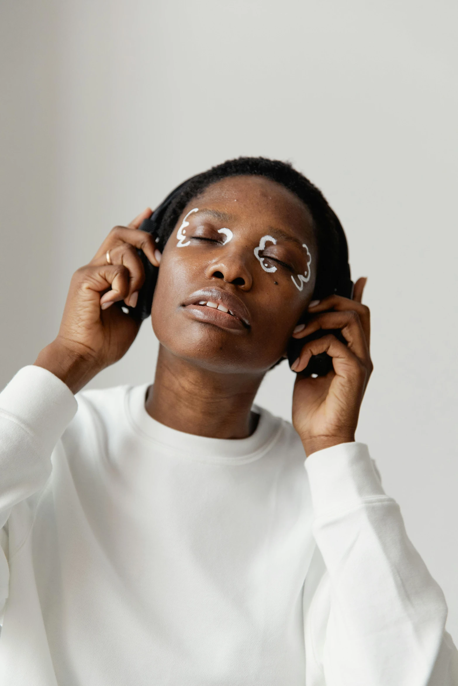 a woman in a white shirt talking on a cell phone, by Dulah Marie Evans, trending on pexels, afrofuturism, white around right eye, photoshoot for skincare brand, on grey background, eyepatches