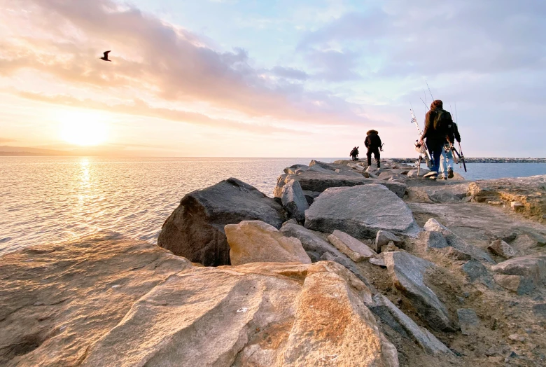 a group of people walking along a rocky beach, by Niko Henrichon, pexels contest winner, near a jetty, fishing, thumbnail, brown