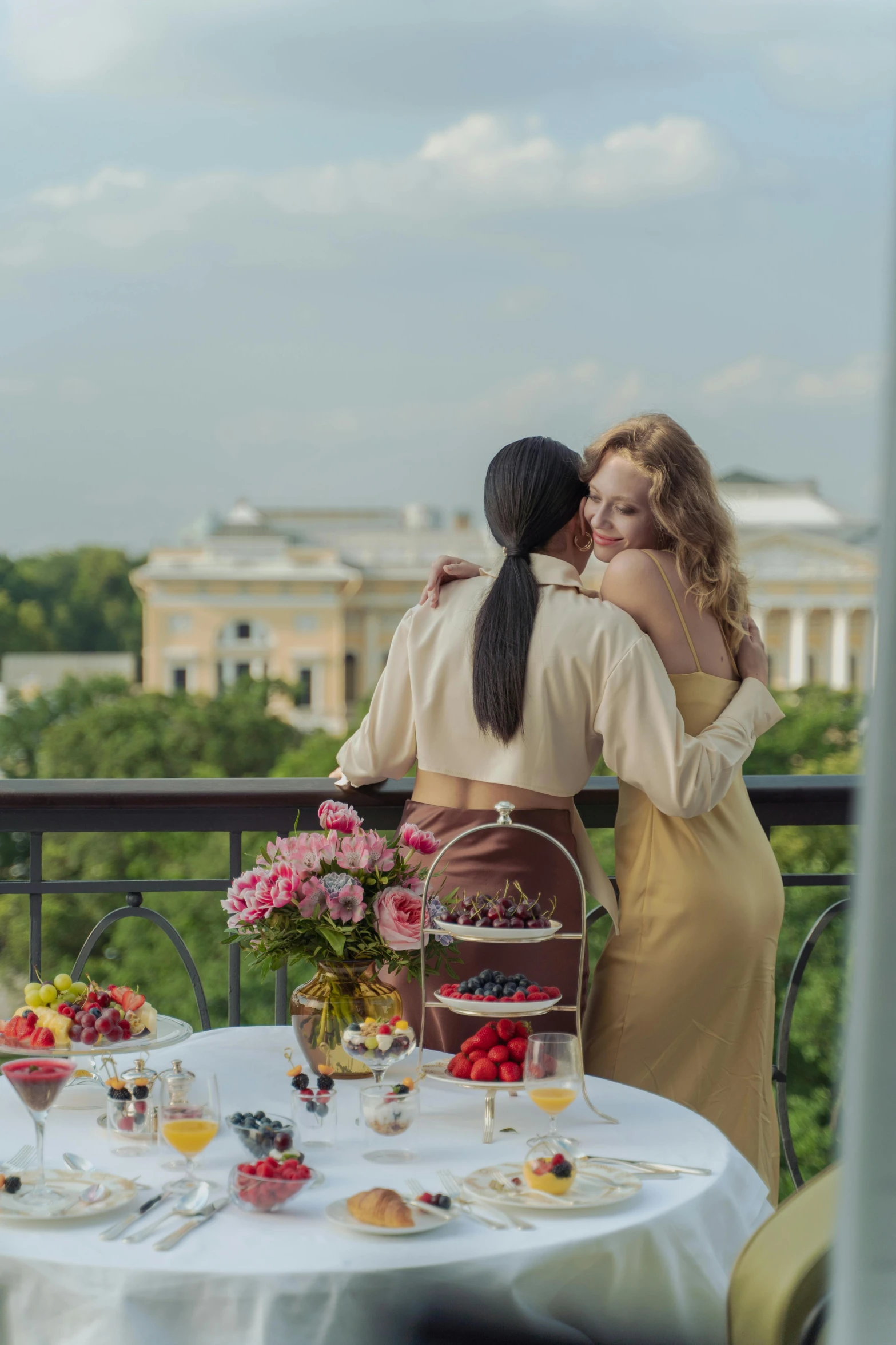 two women sharing an emce in front of a balcony overlooking the city