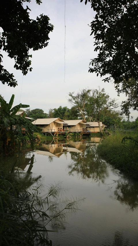 a large body of water surrounded by trees, by Yosa Buson, huts, patiphan sottiwilaiphong, exterior shot, outside