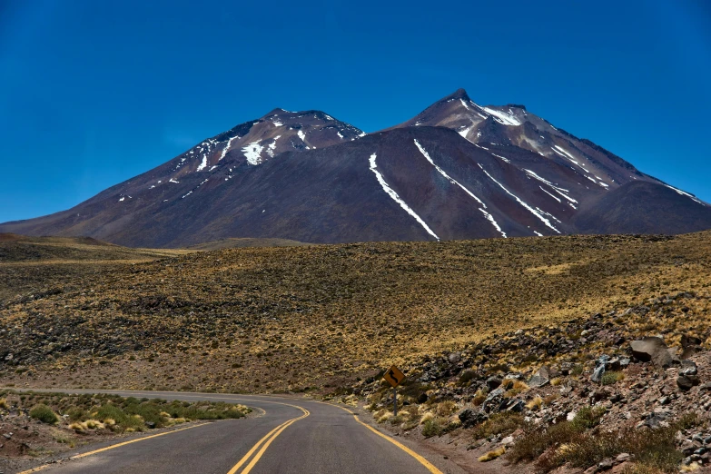 a road running into the mountains with snow on the top