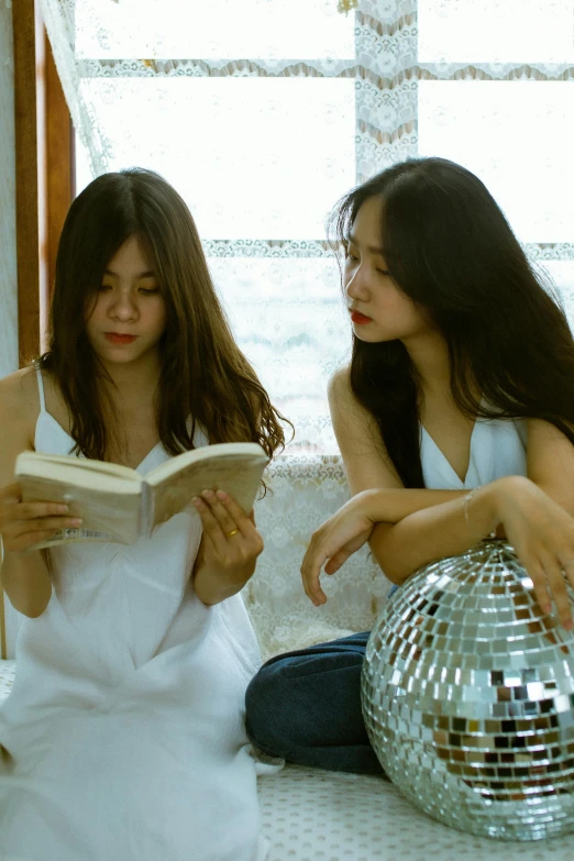 a couple of women sitting on top of a bed, an album cover, by Jang Seung-eop, pexels contest winner, reading a book, dressed in a white t-shirt, in style of lam manh, reading for a party