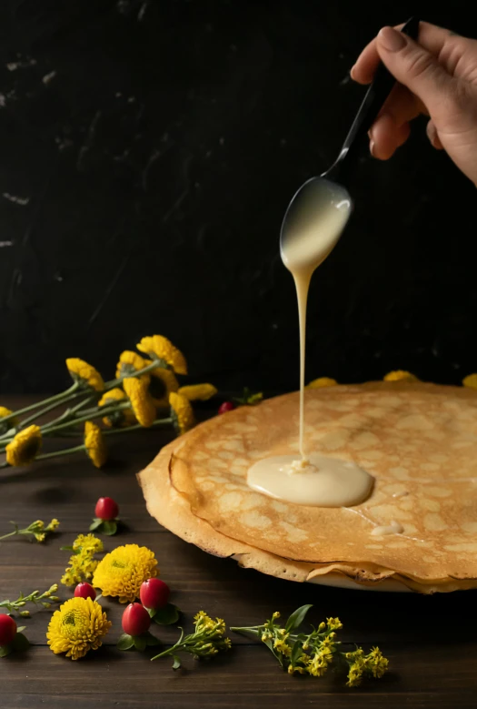 a person dipping cream over a pancake on a table