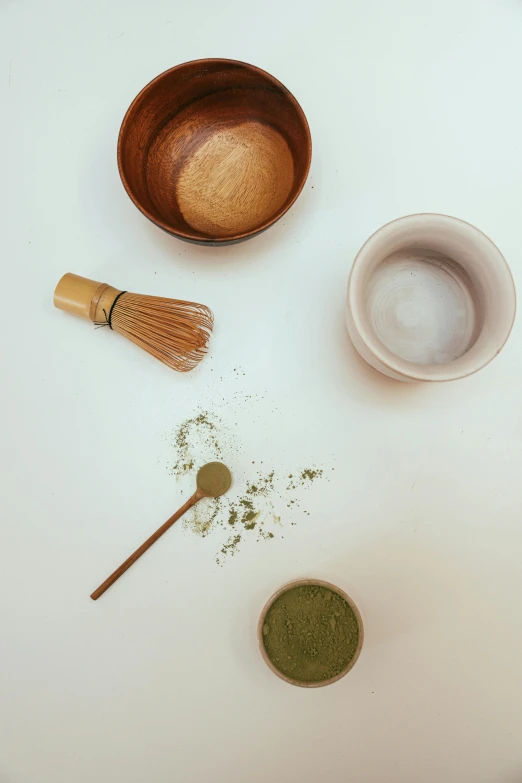 a white table topped with bowls and a whisk, a still life, inspired by Kanō Shōsenin, trending on unsplash, green tea, powder, cosmetics, a wooden