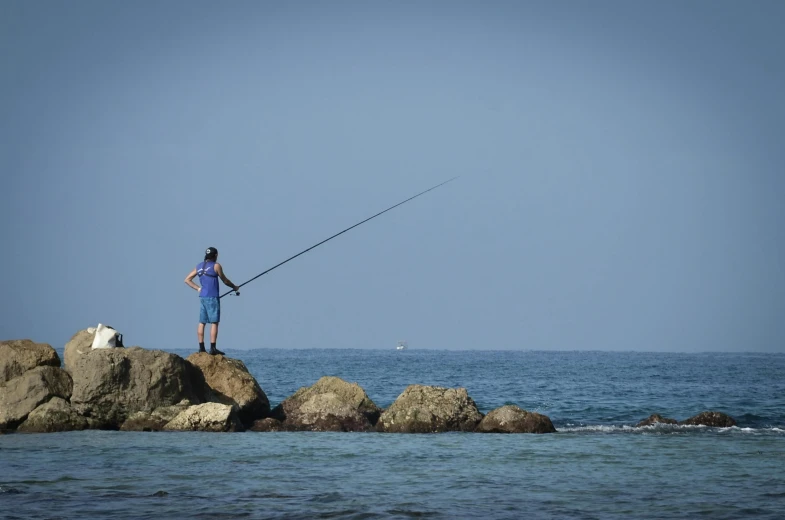 a man standing on a rock with a fishing rod