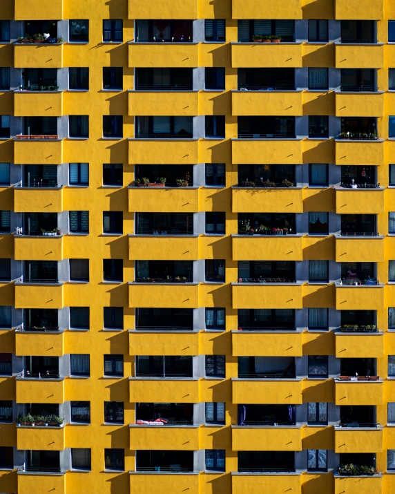 a building made up of yellow colored windows with white balconies