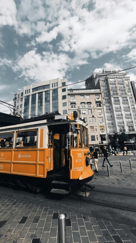 an orange trolley traveling down a street next to tall buildings, by irakli nadar, pexels contest winner, art nouveau, chilean, trams ) ) ), low quality photo, paisley